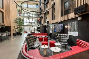 un hall avec des chaises et des tables rouges dans un bâtiment dans l'établissement Radisson RED Aarhus, à Aarhus