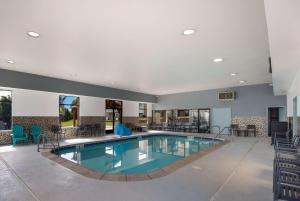 a pool in a hotel lobby with chairs and tables at SureStay Plus Hotel by Best Western Coralville Iowa City in Coralville