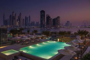 a pool with umbrellas and a city skyline at night at Radisson Beach Resort Palm Jumeirah in Dubai