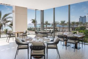 a restaurant with tables and chairs and a view of the ocean at Radisson Beach Resort Palm Jumeirah in Dubai