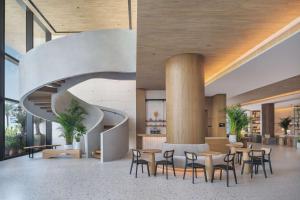 a lobby with a spiral staircase and tables and chairs at Radisson Beach Resort Palm Jumeirah in Dubai