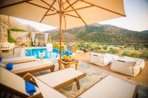 Un patio con sillas y sombrilla y una piscina. en Traditional Villa Askyfou, en Karés