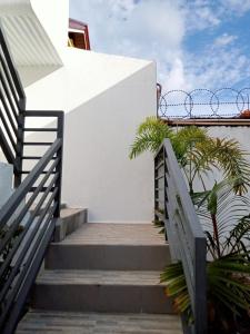 a stairway leading up to a white building with palm trees at __APlaridel Inn Suites__ in Angeles