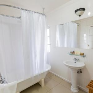 baño con cortina de ducha blanca y lavamanos en Puerto Bories House, Country Houses in Patagonia en Puerto Natales