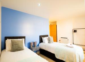 - 2 lits dans une chambre aux murs bleus dans l'établissement Large Apartment - Eleven Charlotte House x 2 Bathrooms, à Ipswich
