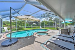 - une piscine avec un parasol et des chaises dans l'établissement Family-Friendly Palm River Estates House!, à Naples