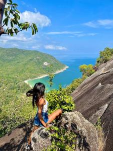 a little girl sitting on a rock looking at the ocean at Arena Seaview in Baan Tai