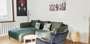 ein Wohnzimmer mit einer grünen Couch und einem Stuhl in der Unterkunft Liebevoll Gästewohnungen in Alpirsbach