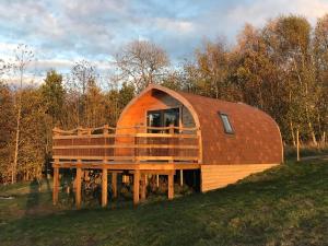 a round house with a wooden deck in a field at Fox’s Furrow Quirky Glamping Pod with Private Hot Tub 