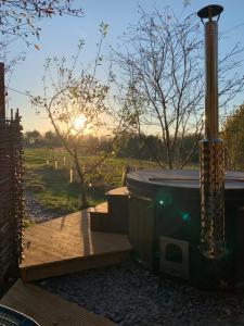 a hot tub in a garden with the sunset in the background at Fox’s Furrow Quirky Glamping Pod with Private Hot Tub 