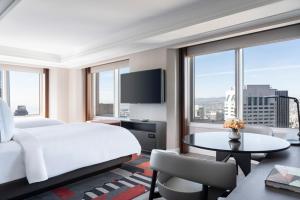 サンフランシスコにあるFour Seasons Hotel San Francisco at Embarcaderoの大きなベッドと景色を望むテーブルが備わるホテルルームです。