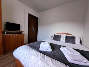 - une chambre avec un grand lit et des serviettes dans l'établissement Aviliz Apartament Bușteni, à Buşteni