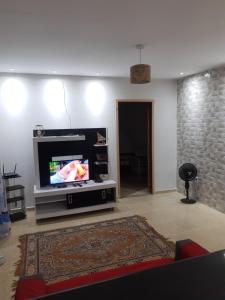 uma sala de estar com uma televisão de ecrã plano num centro de entretenimento em ADN Aluguel e Temporada em Arraial do Cabo