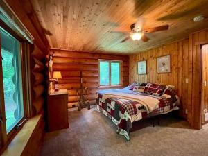 1 dormitorio con 1 cama en una cabaña de madera en Camp Voyager Log Cabin resort pool, golf, trails, lakes more, en Webb Lake