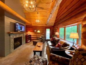 sala de estar con sofá y chimenea en Camp Voyager Log Cabin resort pool, golf, trails, lakes more, en Webb Lake
