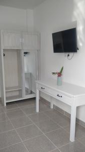 uma sala de estar com uma mesa branca e uma televisão na parede em Anjo Maumere Hotel & Restaurant em Nangalima