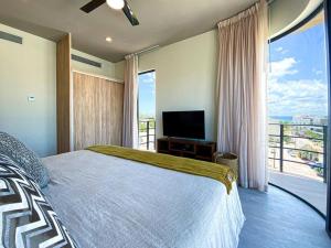 a bedroom with a bed and a television and a balcony at Beautiful + Luxury + Ocean View + Pool in Playa del Carmen