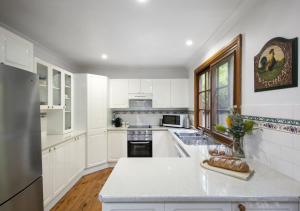 a kitchen with white cabinets and a stainless steel refrigerator at Cants Cottage in Broke