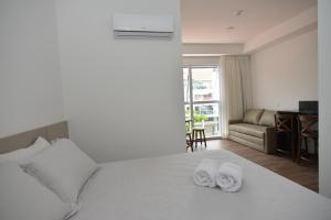 a hotel room with a bed with towels on it at Vila do Centro Apart Hotel in Bombinhas