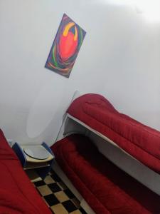 Un dormitorio con una cama roja y una bandera en la pared en Casa de Barro Tilcara en Tilcara