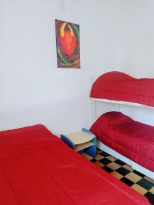 a bedroom with two beds with red covers and a table at Casa de Barro Tilcara in Tilcara