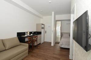 a living room with a couch and a kitchen at Vila do Centro Apart Hotel in Bombinhas