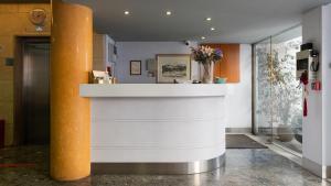 a lobby with a white counter and an orange pillar at Diros Hotel in Athens
