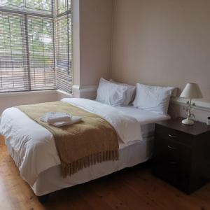 a bedroom with a large white bed and a window at Esperamos in Durban