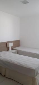 a bedroom with a large bed and a table at Residencial Iloa in Barra de São Miguel +4 photos
