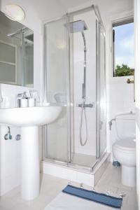 een witte badkamer met een wastafel en een douche bij Leeward Suite @ Fiscardo Waterfront in Fiskardho