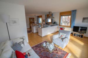 Una sala de estar con un sofá blanco y una cocina. en Chasa Weekend, en Scuol