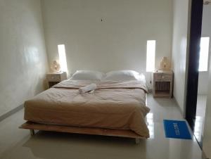 Ce lit se trouve dans un dortoir blanc doté de 2 tables de nuit. dans l'établissement Yanti Guest House, à Canggu