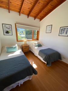 two beds in a room with a window at Casa Roma in Villa La Angostura