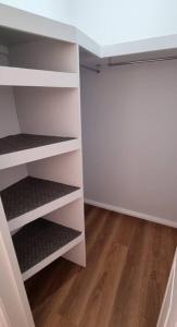 an empty closet with white shelves and a wooden floor at Guest Studio in Campbelltown 