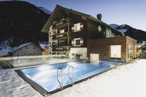 a house with a swimming pool in the snow at Hotel Schwarzer Adler - Sport & Spa in Sankt Anton am Arlberg