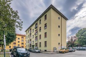 a yellow building with cars parked in a parking lot at House MaGa - by Host4U in Brescia