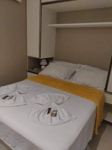 a large white bed with a yellow blanket on it at Eco Resort Praia dos Carneiros - Flat 116CM, apartamento completo ao lado da igrejinha in Praia dos Carneiros