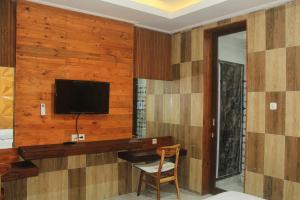 DarmasabaAnny Guesthouse by ecommerceloka的客房设有木墙、电视和椅子。