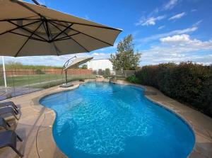 ein großer blauer Pool mit Sonnenschirm in der Unterkunft Ranch House in Bakersfield