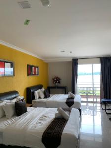 a hotel room with three beds and a balcony at Lumuda Hotel in Lumut