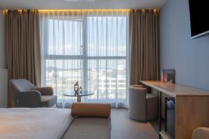 ein Hotelzimmer mit einem Bett und einem großen Fenster in der Unterkunft Brown Dot Siheung Geobuksum in Siheung