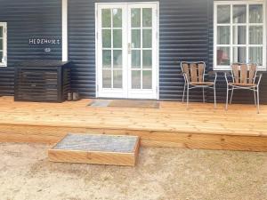 une terrasse en bois avec deux chaises et une table sur une maison dans l'établissement 8 person holiday home in R m, à Kongsmark