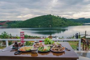 a table with plates of food on it with a view of a river at Thỏ Non Garden Villa Bảo Lộc in Bao Loc