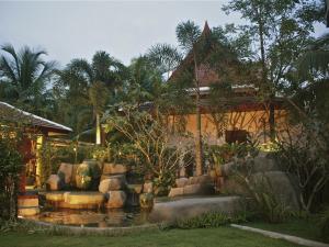 a garden with a pond in front of a house at Fanari Khaolak Resort - Courtyard SHA Extra Plus in Khao Lak