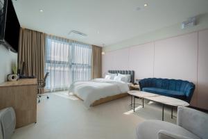 una camera con un letto e un divano blu di Brown Dot Siheung Geobuksum a Siheung