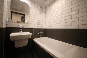ein Badezimmer mit einem Waschbecken, einer Badewanne und einem Spiegel in der Unterkunft 25 Hotel in Uiwang