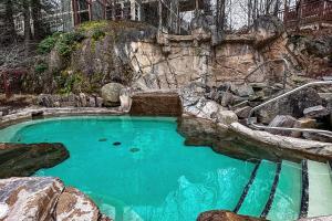 une grande piscine d'eau bleue avec un mur de roche dans l'établissement Tremblant-Les-Eaux Le Contemporain by Gestion ELITE, à Mont-Tremblant
