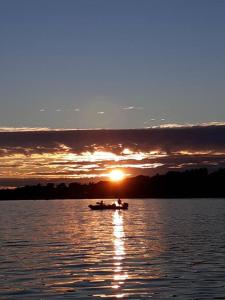 a boat on the water with the sunset in the background at Overlook Lakehouse on Chippewa Lake Close to Haymarsh State Game Area and Ferris State College in Barryton