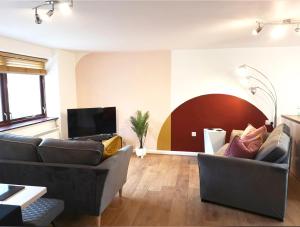 uma sala de estar com dois sofás e uma televisão em Maltings House Cosy and Stylish 2 bedroom flat near the city centre with free parking and ensuite rooms em Carlisle
