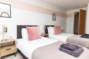2 camas en una habitación de color rosa y blanco en Maltings House Cosy and Stylish 2 bedroom flat near the city centre with free parking and ensuite rooms en Carlisle